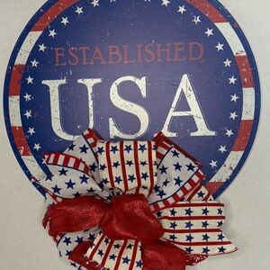 Patriotic USA Round Wall Decor with Red, White & Blue Bow sign is 12 inches